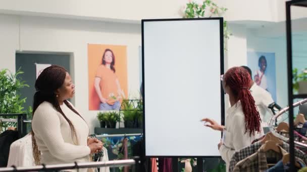 Giyim Mağazasında Çalışan Bir Müşteri Dijital Ekran Kullanarak Gömlekler Arasından — Stok video