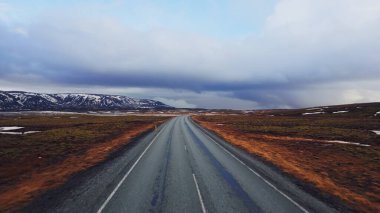 Büyük yollar ve karlı dağ tepeleri, İzlanda 'da donmuş yeşil alanlar, muhteşem manzaralı kuzeyli yol manzarası. İskandinav doğası ve İzlanda manzaraları.