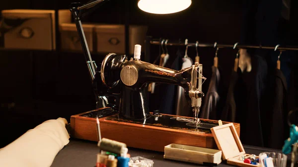 Old school sewing machine in atelier, fashion industry with tailoring tools used to create custom made clothing line. Textile industry with professional instruments and workstations. Close up.
