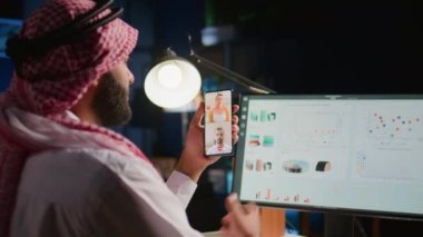 Evde çalışan müslüman amir ve çalışanlar verileri kontrol ediyor. Arap yönetici anahtar performans göstergelerini optimize ederek, telekonferans toplantısındaki ilerlemeyi astlarıyla tartışıyor