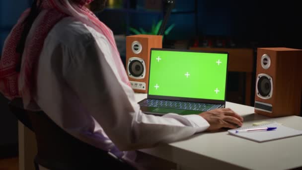在家里工作的时候 一个阿拉伯人在电脑上打滚 在以电视为背景噪音的公寓办公室隔离屏幕设备上写电子邮件的自营职业者 — 图库视频影像