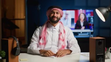 Neşeli bir Arap, öğretmeniyle yapılan seminer telekonferansına dikkat ediyor. Çevrimiçi videodaki Orta Doğulu öğrenci selamlama öğretmeni, ödev yazarken ders dinliyor