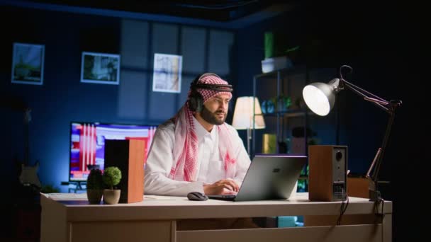 Arab Man Med Trådlösa Hörlurar Hemma Vardagsrummet Tittar Utbildningsvideor Bärbar — Stockvideo
