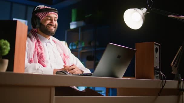 Арабський Чоловік Бездротовими Навушниками Вдома Вітальні Дивиться Відео Ноутбук Безтурботний — стокове відео