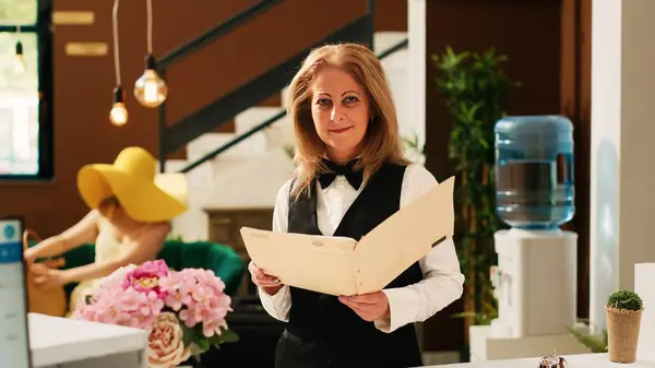Hotel concierge reviewing bookings or reservations, working at reception in lobby to help travellers with check in procedure. Receptionist in front desk, tropical exotic resort.