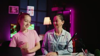 Z jenerasyonu izleyicileri için videolar çeken kız ve anne dizüstü bilgisayardaki videolara bakmaya hazırlanıyor. Sevimli çocuk ve ailesi aile kanalı için internet kliplerine tepki gösteriyor.