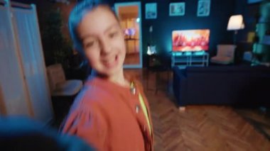 Çocuk, mavi neon ışıklı oturma odasında akıllı telefonlu POV tarzı dans dersleri videosu çekiyor. Genç dansçı viral sosyal medya dans yarışması yapıyor, selfie cep telefonu kamerasıyla çekim yapıyor.