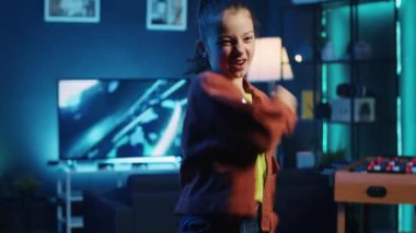 Sosyal ağ platformları için büyüleyici dans hareketleri yapan heyecanlı bir kızın viral meydan okuma sahnesini çekin. Güler yüzlü çocuk, loş ışıklı ev stüdyosunda çevrimiçi hayranları için video kaydediyor.