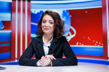 Haber spikeri stüdyoda canlı yayında küresel sorunlarla ilgili son dakika haberlerini sunmaya hazırlanıyor. TV programında eğlence bölümüne ev sahipliği yapan kadın gazeteci.