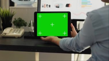 Yaratıcı ajans ortak çalışma alanında yeşil ekranı kontrol eden bir kadın, krom anahtar ekranına bakıyor ve mobil cihaz düzeninde izole edilmiş bir model var. Çalışan elinde bir model aygıtı tutuyor.