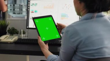 Ofis çalışanı birlikte çalışma alanındaki yeşil ekran düzenini inceliyor, iş operasyonları üzerinde çalışıyor ve izole edilmiş kromakey ekrana bakıyor. Boş telif alanı olan tableti tutan kadın.