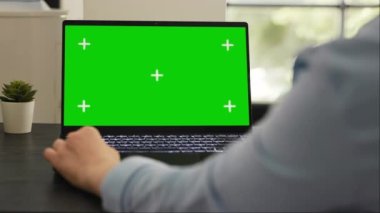 Kadın yönetici, dizüstü bilgisayarda izole edilmiş yeşil ekran şablonu üzerinde çalışıyor, boş maket ekran ile bilgisayarı kontrol ediyor. Kromakey telif alanı düzeni kullanarak başlangıç görevleri üzerinde çalışan genç yetişkinler.