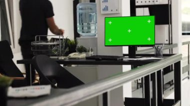 Ajansın ortak çalışma alanındaki ofis masasında çalışan işletme yöneticisi, kromakey ekran ve izole model düzeniyle bilgisayar masaüstünü kullanıyor. Şirket çalışanı boş monitörü kontrol ediyor.