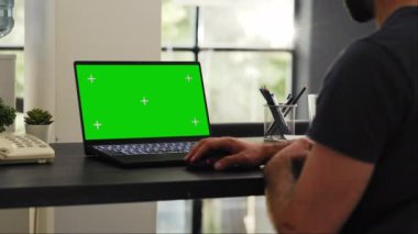 Erkek çalışan dizüstü bilgisayardaki yeşil ekrana bakar, ofis çalışma alanındaki izole kromakey düzenini kontrol eder. Modern masadaki boş telif alanı şablonunu inceleyen bir işadamı.