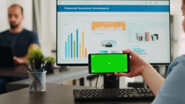 Cep telefonunda izole edilmiş yeşil ekran kullanırken, telif alanı üstüste binen boş model ekrana odaklanan bir işletmeci. Kromakey şablonu ile akıllı telefon görüntüsünü inceleyen çalışan.