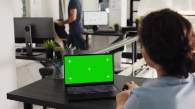 Çalışan dizüstü bilgisayarda yeşil ekran düzeni kullanır, iş operasyonları ve pazarlama görevleri üzerinde çalışır. Uzman, açık ofiste izole edilmiş bir kopya uzay şablonu ile bilgisayarı inceliyor. El kamerasıyla..
