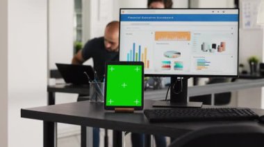 Yeşil ekran tabletli boş masa ve çalışan bilgisayar, iş işleri için ortak çalışma alanı. Alet üzerinde boş kromakey modelleme yazılımıyla çalışma istasyonunda bilgisayar masaüstü.