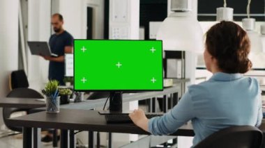 Bilgisayarda yeşil ekran ekranı kullanan bir uzman, küçük işletme ofisindeki pazarlama işlemleri üzerinde çalışıyor. Masadaki bilgisayarda izole edilmiş kromakey şablonu olan kadın gözden geçirme stratejisi.