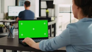 İş adamı başlangıç ofisinde yeşil ekran şablonu olan kromakey laptop kullanıyor. Şirket çalışanı kablosuz bilgisayar ekranında izole edilmiş modeliyle kopyalama alanına bakıyor.