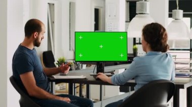 Şirket ekibi, küçük işletme geliştirme biriminde otururken monitörde yeşil ekran kullanıyor. Erkek ve kadın meslektaşlar izole edilmiş boşlukları gösteriyorlar.