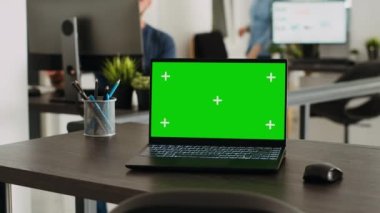 Yaratıcı ajans işyerindeki boş masada yeşil ekranlı kablosuz bilgisayar, ekranda boş telif alanı gösteren dizüstü bilgisayar. Girişimcilik işi yapan insanlar, çalışma istasyonu ve model şablonu.
