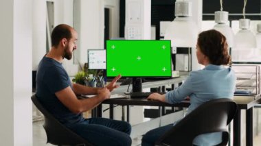 Başlangıç ekibi yeşil ekran, küçük ofis masası olan bilgisayara bakıyor. Şirket çalışanları izole edilmiş telif alanı şablonunu analiz ediyor, gelir geliştirme için takım çalışması yapıyor, görüntüde kromakey.