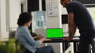 İş dünyası ekibi birlikte çalışan uzay ofisindeki yeşil ekran görüntüsünü gözden geçirir. Başlangıç gelişimi için beyin fırtınası fikirleri, boş model şablonu. Meslektaşlar krom ekranlı dizüstü bilgisayar kullanır. El kamerasıyla..