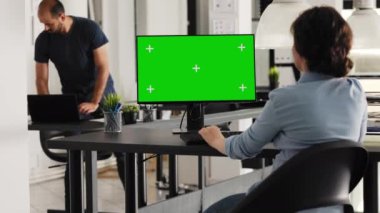 İş kadını bilgisayar bilgisayarında yeşil ekranla çalışıyor. Ajans ofisinde birlikte çalışıyor. Genç yetişkin çalışan, kromakey ile izole edilmiş görüntüyü gösteren bilgisayar monitörünü inceliyor.