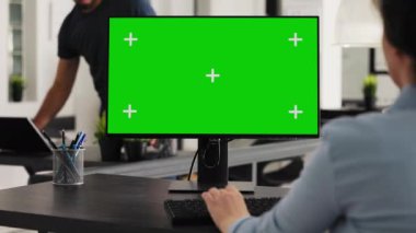 Masasında yeşil ekran masaüstü ile çalışan bir işçi, izole edilmiş bilgisayar düzenini kromakey telif alanı şablonuyla analiz ediyor. Başlangıçta çalışmak için bilgisayardaki boş ekranı kullanan kadın.