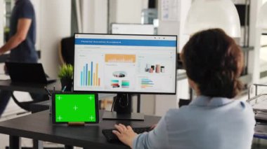 İş kadını, bilgisayardaki gelir verilerini analiz ederken izole edilmiş bir telif alanı şablonuna bakarak, modern tablette sunulan yeşil ekran ile masada çalışıyor. İşçi kromakey ekran kullanır. El kamerasıyla..