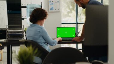 Başlangıç ekibi dizüstü bilgisayar düzeni için yeşil ekran uygulamasını kontrol ediyor, yeni bütçe fikirleri üzerinde beyin fırtınası yapıyor ve iş operasyonları üzerinde çalışıyor. Çalışma masasında tartışan meslektaşlar, izole kromakey ekran.