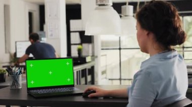 Müdür dizüstü bilgisayarda yeşil ekranla çalışıyor. Yaratıcı ajans ofisindeki izole modelleme şablonlarını kontrol ediyor. Ekranda boş kromakey düzeni ve modern yazılım gösteren genç yetişkinler.