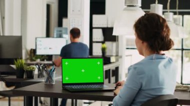 Girişimci, yaratıcı ajans açık uzay ofisinde çalışan yeşil ekranı kontrol ediyor, boş model ekrana bakıyor. İşyerinde izole edilmiş kromakey görüntüsünü analiz eden uzman.