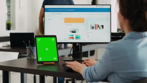 エージェンシーの従業員は グリーンスクリーンでタブレットを見て コンピュータ上の情報を入力し 現代のガジェットのモックアップテンプレートをチェックしています オフィスの染色体とのビジネスに携わる女性 — ストック動画