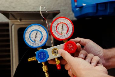 Klima kontrolü yapılırken manifold göstergelerini ayarlayan usta işçilere yakın çekim yapın. Sertifikalı teknisyen soğutma sisteminde potansiyel yüksek basınç arıyor