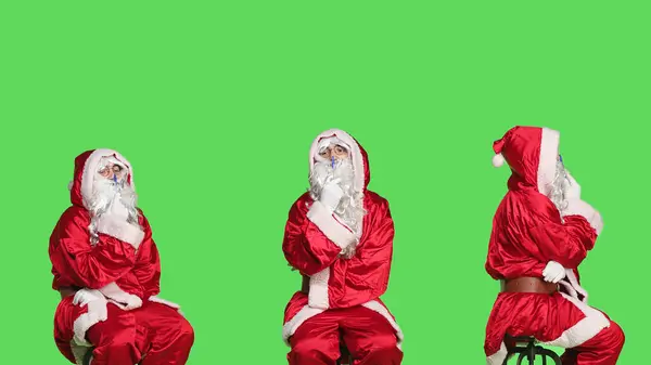 圣诞老人坐在椅子上头脑风暴般的礼物概念坐在绿屏的背景上 想着圣诞节前夕的礼物 在演播室里打扮成圣人尼克的年轻人 — 图库照片