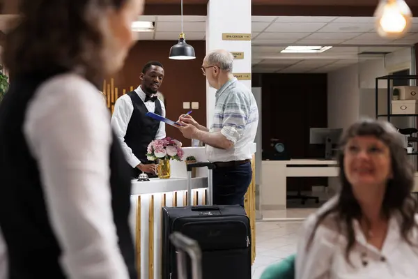 Африканский Американский Консьерж Помогает Пожилым Пенсионерам Вестибюле Отеля Обеспечивая Беспрепятственную — стоковое фото
