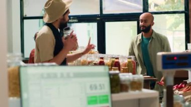 Tüccar kasada terazi kullanıyor, gıda malzemeleri tartıyor ve marketteki Orta Doğulu alıcılar için taze ürünler alıyor. Tedarikçi, yerel süpermarkette bir adama toplu halde kiler satıyor. El kamerasıyla..