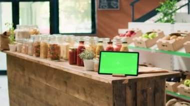 Yeniden kullanılabilir konteynırlardaki toplu ürünlere bakan bir kadının yanındaki yeşil ekran. Müşteriler yerel sıfır atık dükkanında sağlıklı yaşam tarzını teşvik ediyor. Tabletteki izole edilmiş krom anahtar şablonu.