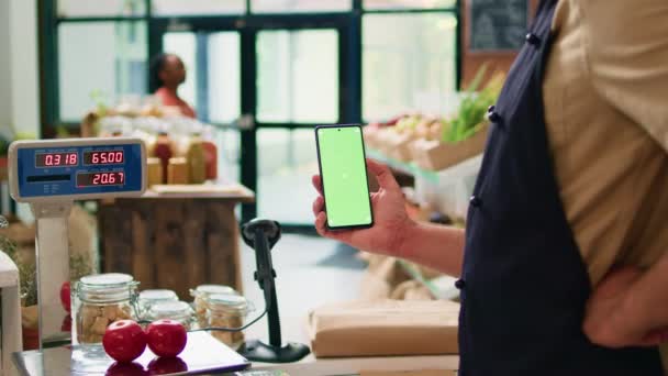 Junger Mann Hält Smartphone Der Ladenkasse Und Präsentiert Isolierte Greenscreen — Stockvideo