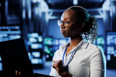 Yüksek teknoloji işletmesindeki becerikli yönetici sistemin aşırı yüklenmesini önlemek için dizüstü bilgisayar kullanır. Düzgün işlemler için yeterli ağ bant genişliğini sağlayan sunucu dolapları arasındaki yetkili uzman