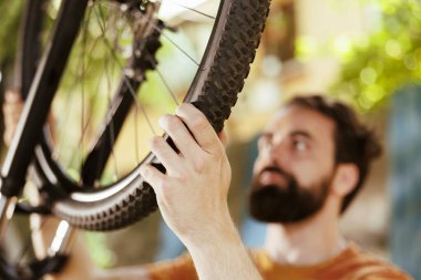 Bahçede sökülmesi için bisiklet lastiği lastiği tutan genç adamın detaylı görüntüsü. Görüntü, kişinin el kamerasıyla zarar görmüş bisiklet lastiği tüpünü tamir ederken görüntülemesi.