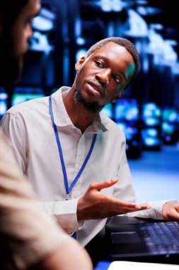 Sunucu odası arızalarıyla ilgilenen Afrikalı Amerikalı uzman ve iş arkadaşı. Bilgisayar bilimcileri veri merkezi ekipmanlarını en aza indirmek ve kazaları önlemek için beyin fırtınası yapıyorlar.