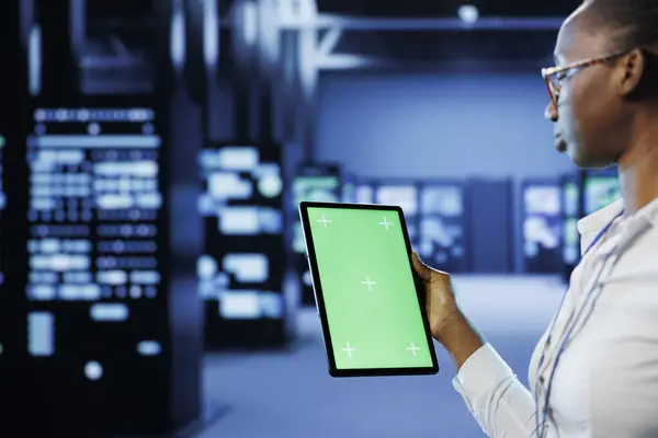 stock image Technician in server room using green screen tablet to future proof network from downtimes and unexpected system failures. Expert with chrome key device ensuring increased data security