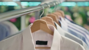 Lüks giyim mağazasında askı takan şık gömlek çeşitlerinin aşırı yakın çekimi. Premium moda butiğindeki yeni koleksiyondan moda şık üst sınıf kıyafetler.