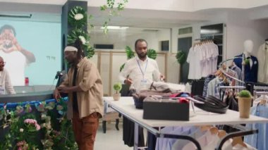 Çalışanlar ikinci el dükkanını ucuz ve şık resmi gömleklerle dolduruyorlar. İkinci el giyim mağazasında satıcı. Müşterilerle dolu. Arazi dolgusundan kurtarılan yeni kıyafetlerle rafları dolduruyorlar.