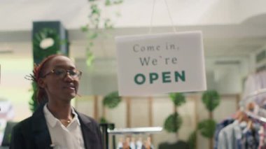 Afro-amerikan mağaza asistanı moda butiği işini kapatıyor, gece vardiyası bitiyor. Dükkan sahibinin hızlı moda mağazasındaki tabelayı çalışma saatlerinden sonra kapatması.