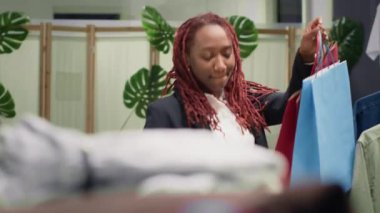 Kadın, tanıtım sezonunda giysi mağazasında dans ediyor. Gardırobunu dolduracak ucuz kıyafetler bulduktan sonra. Alışveriş çantalı müşteri moda mağazasındaki satışlardan faydalanıyor.