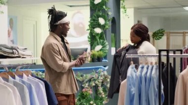 Lüks moda butiklerinde raflarda şık kıyafetler arayan genç bir çift. Afrikalı Amerikalı müşteriler tasarımcı giyim mağazasından özel durumlar için erkek gömleği alıyorlar.
