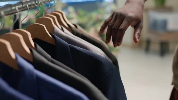 节俭商店里的顾客在货架上浏览衣服以寻找完美的服装 顾客在二手服装店购物的特写镜头 想购买雅致的运动衫 — 图库视频影像